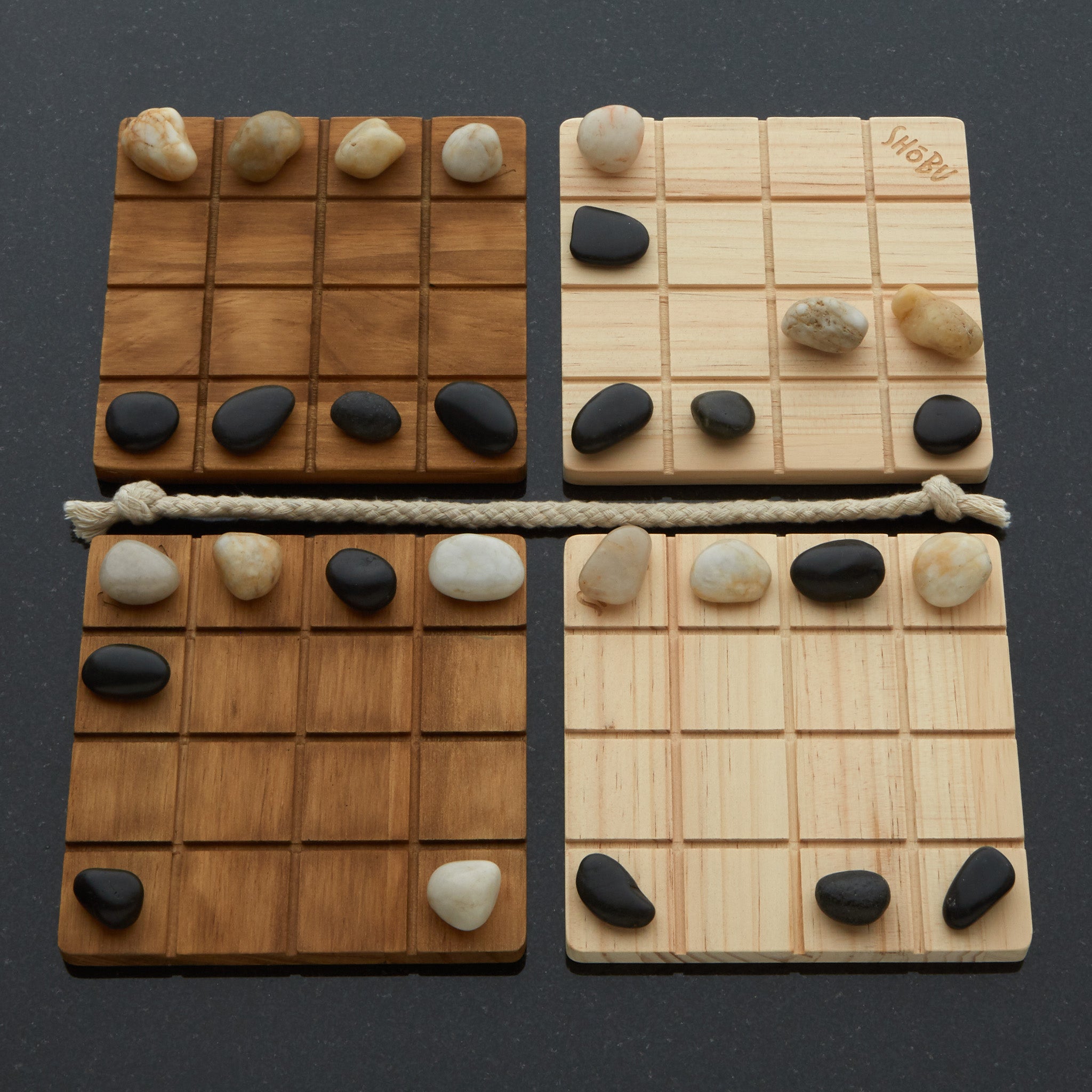 Four wooden boards with grid patterns and stones on a dark background