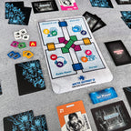Board game components including cards and a map on a gray surface