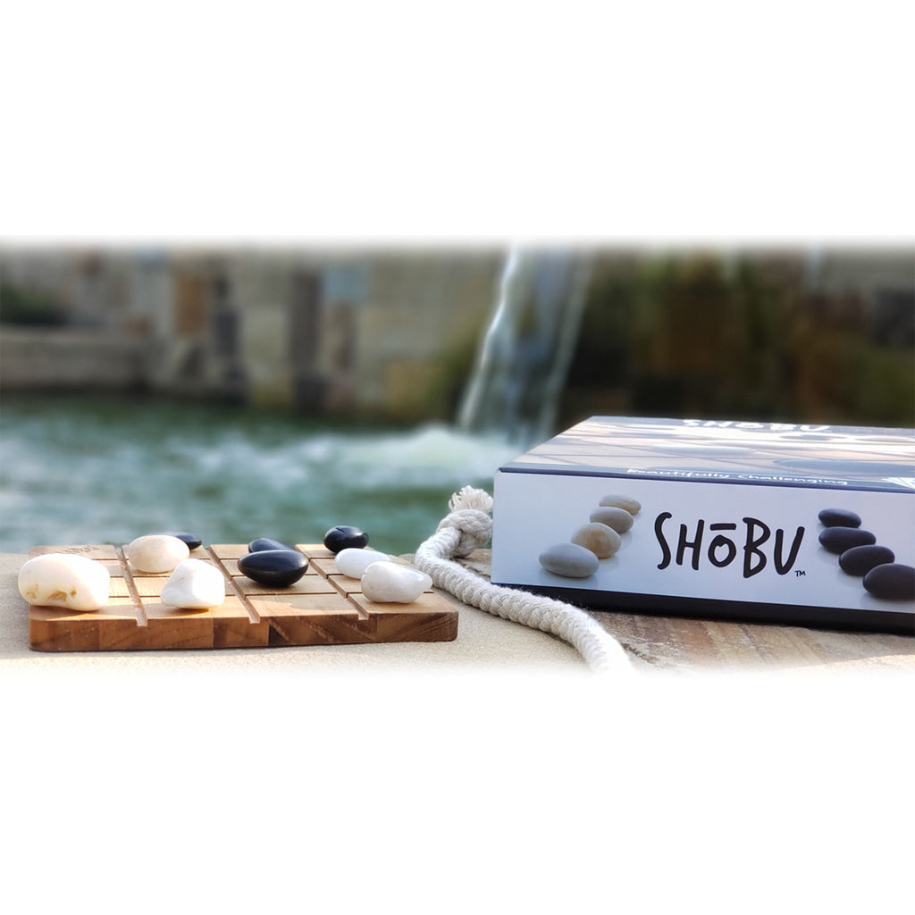 SHÜbö product with stones and candles on a wooden board by a water feature