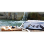 SHÜbö product with stones and candles on a wooden board by a water feature