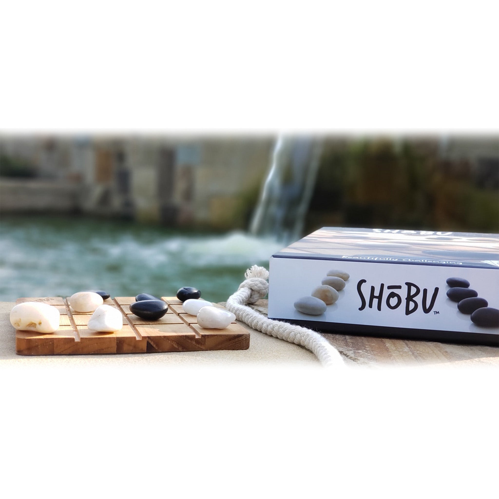 SHÜbö product with stones and candles on a wooden board by a water feature